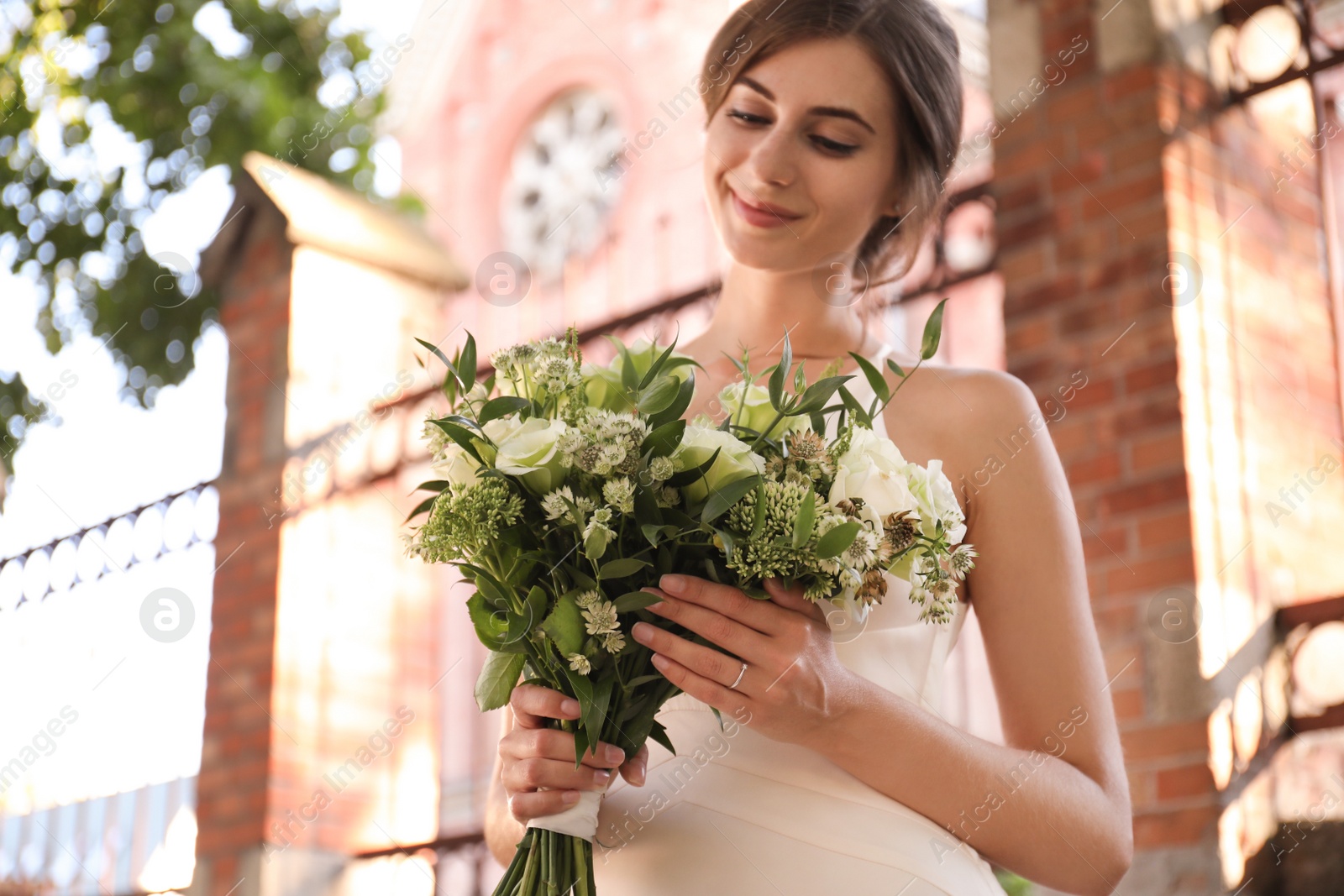 Photo of Gorgeous bride in beautiful wedding dress with bouquet near church