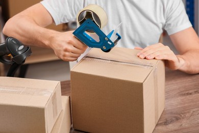 Photo of Post office worker packing parcel at counter indoors, closeup