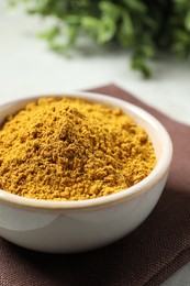 Photo of Curry powder in bowl on white table, closeup