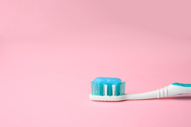 Photo of Brush and toothpaste on pink background, space for text