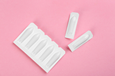 Photo of Suppositories on pink background, flat lay. Hemorrhoid treatment