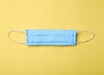 Photo of Homemade protective mask on yellow background, top view. Sewing idea