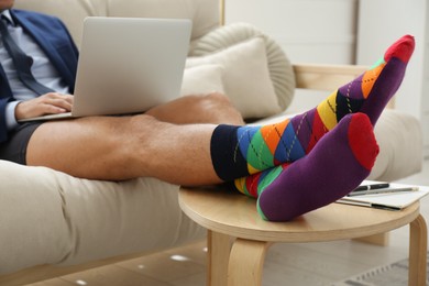 Photo of Businessman in jacket and underwear working on laptop at home, closeup