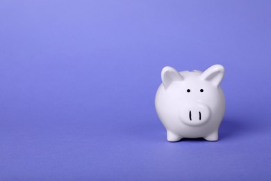 Photo of Ceramic piggy bank on purple background, space for text. Financial savings