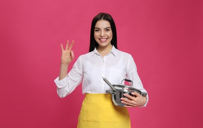 Photo of Young housewife with pan on pink background