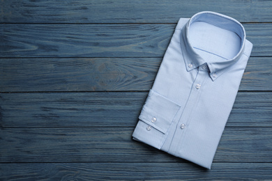 Photo of Male stylish light blue shirt on wooden background, top view. Space for text
