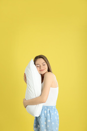 Photo of Young woman with pillow on yellow background