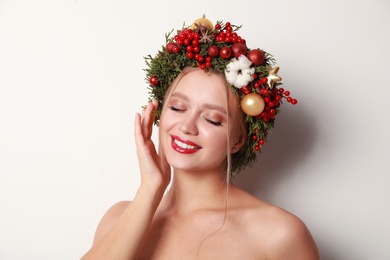 Photo of Beautiful young woman wearing Christmas wreath on white background