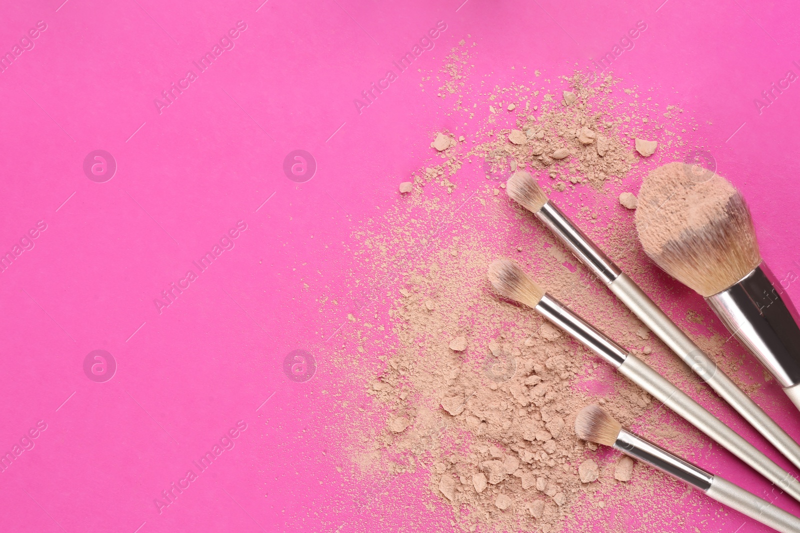 Photo of Makeup brushes and scattered face powder on bright pink background, flat lay. Space for text
