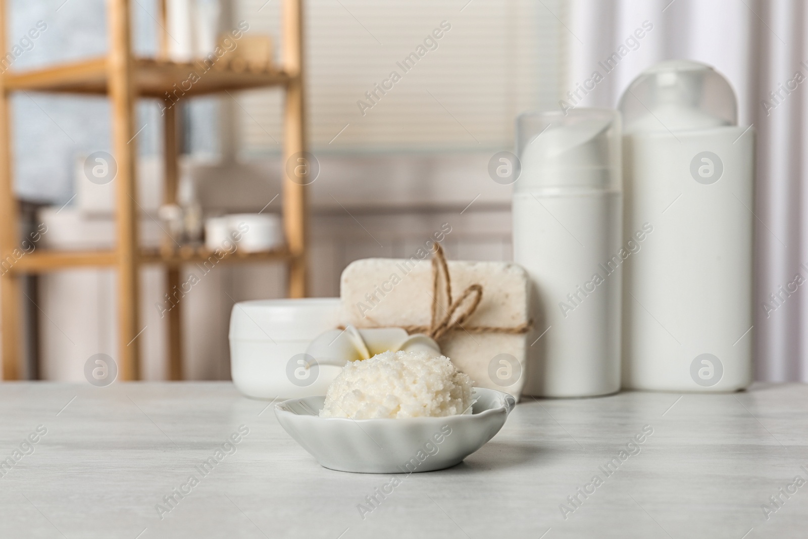 Photo of Bowl with Shea butter and other cosmetic products on table in bathroom. Space for text