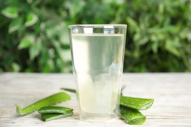 Photo of Fresh aloe drink in glass and leaves on white wooden table