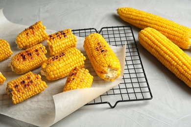 Photo of Cooling rack with grilled corn cobs on light background