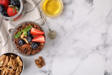 Photo of Tasty granola with berries, nuts, honey and whisk on white marble table, flat lay. Space for text