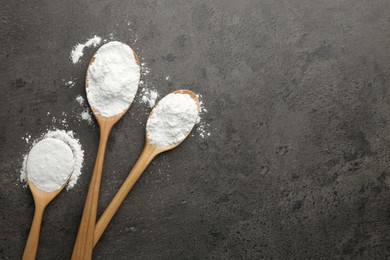 Photo of Baking powder in spoons on grey textured table, flat lay. Space for text