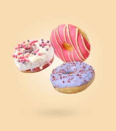 Image of Sweet tasty donuts falling on beige background
