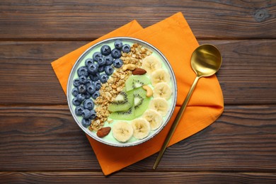 Photo of Tasty smoothie bowl with fresh fruits and oatmeal served on wooden table, flat lay