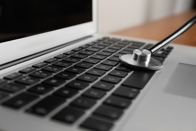 Photo of Modern laptop with stethoscope on table, closeup
