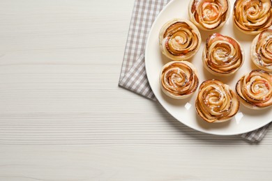 Photo of Freshly baked apple roses on white wooden table, top view. Space for text