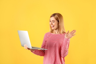Photo of Woman using laptop for video chat on color background