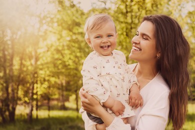 Image of Happy mother with her cute baby in park on sunny day, space for text