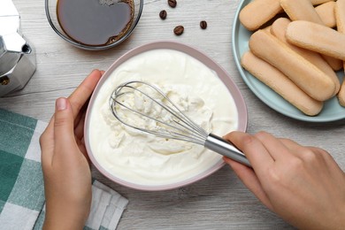 Photo of Woman making tiramisu cake at white wooden table, top view