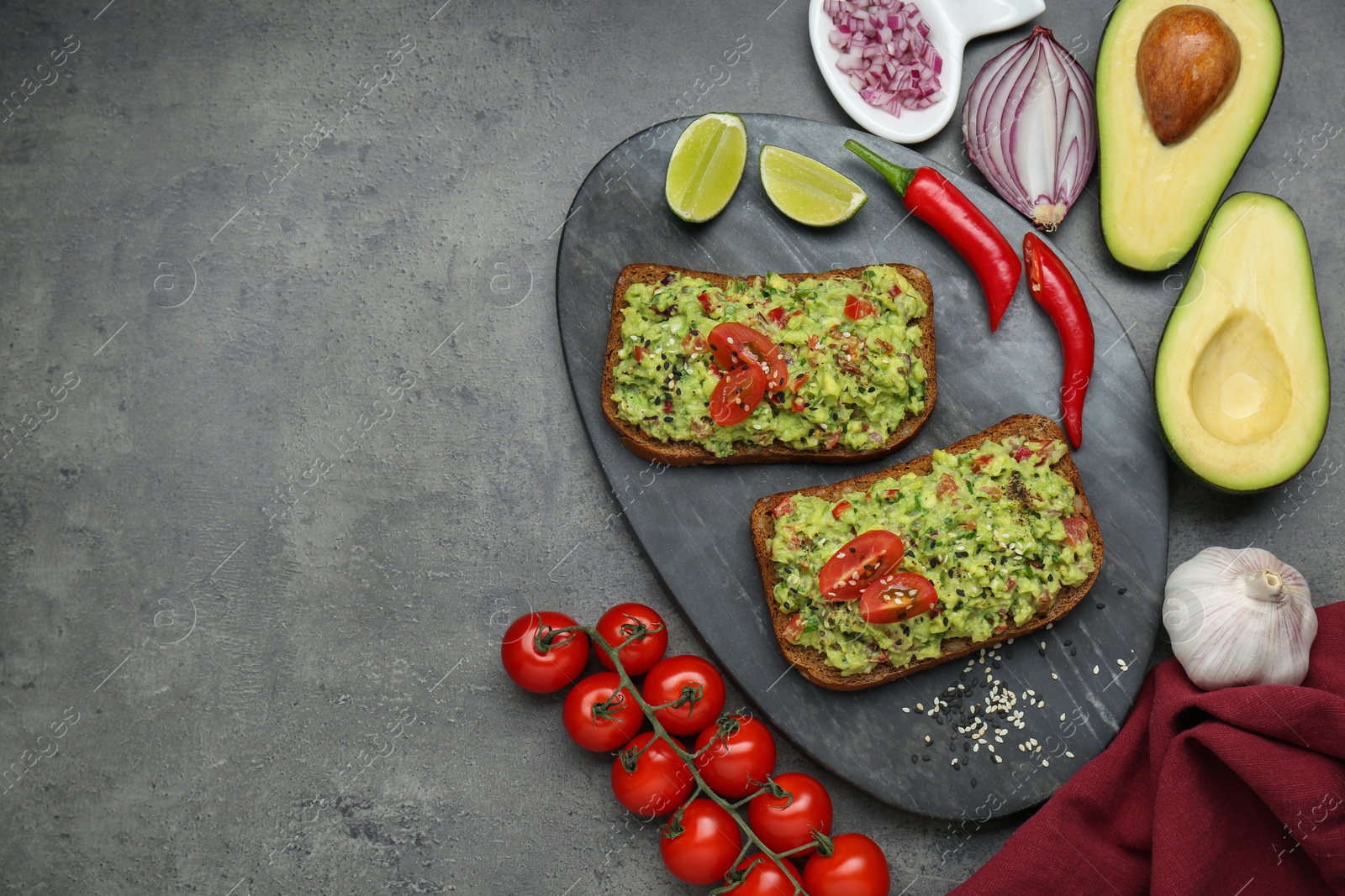 Slices of bread with tasty guacamole and ingredients on grey table, flat lay. Space for text Photo of Slices of bread with tasty guacamole and ingredients on grey table, flat lay. Space for text