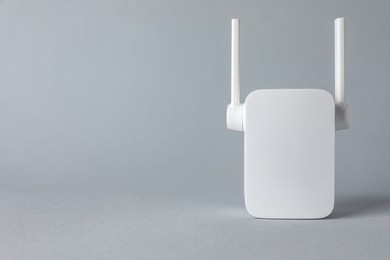 Photo of New modern Wi-Fi repeater on light gray background, space for text
