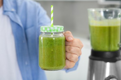 Photo of Man holding mason jar with delicious smoothie indoors, closeup