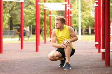 Photo of Young man suffering from knee pain on sports ground