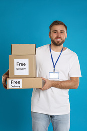 Photo of Male courier holding parcels with stickers Free Delivery on light blue background