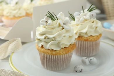 Photo of Tasty Easter cupcakes with vanilla cream on table, closeup
