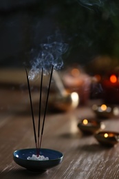 Photo of Incense sticks smoldering on wooden table in room