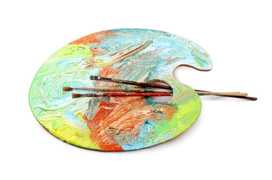 Photo of Artist's palette with mixed paints and brushes isolated on white
