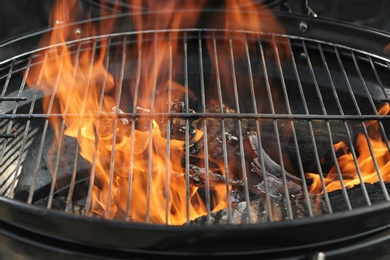 Photo of New modern barbecue grill with burning firewood, closeup