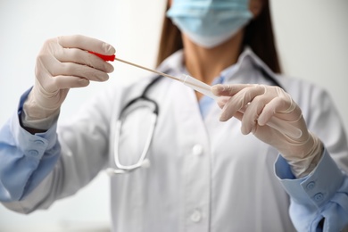 Photo of Doctor holding buccal cotton swab and tube for DNA test in clinic, closeup