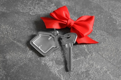 Photo of House key with trinket and bow on grey background