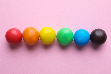Photo of Colorful candies on pink background, flat lay. Rainbow palette