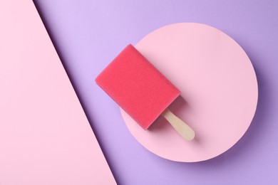 Photo of Sponge with wooden stick as ice cream on color background, top view. April Fools' Day