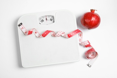 Photo of Composition with scales, tape measure and pomegranate on white background, top view