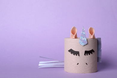 Photo of Toy unicorn made of toilet paper roll on lilac background. Space for text