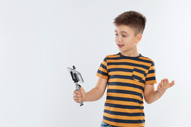 Photo of Cute little blogger recording video on white background