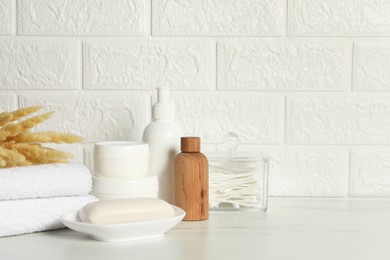 Photo of Different bath accessories, personal care products and spikelets on white table near brick wall, space for text