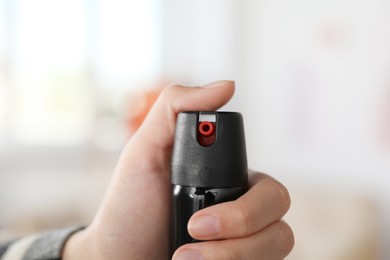 Photo of Woman using pepper spray on blurred background, closeup