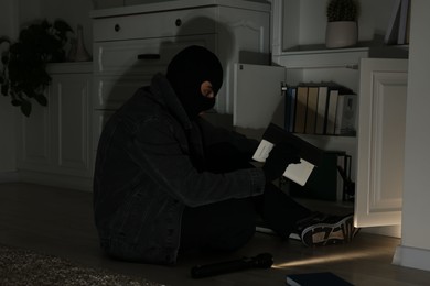 Photo of Thief looking for money near chest of drawers at foreign house. Burglary