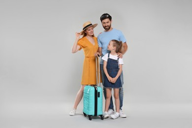 Photo of Happy family with turquoise suitcase on light grey background