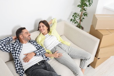 Photo of Happy couple resting on sofa in new apartment. Moving day