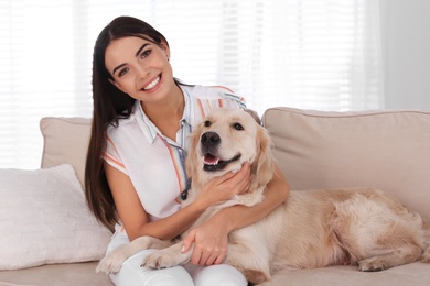 Young woman and her Golden Retriever dog on couch in living room