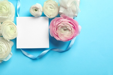 Photo of Beautiful ranunculus flowers with blank card and gift box on color background