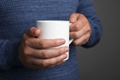 Photo of Man holding white mug on grey background, closeup