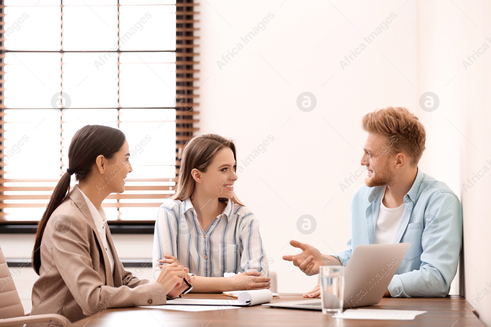 Photo of Female insurance agent consulting young couple in office